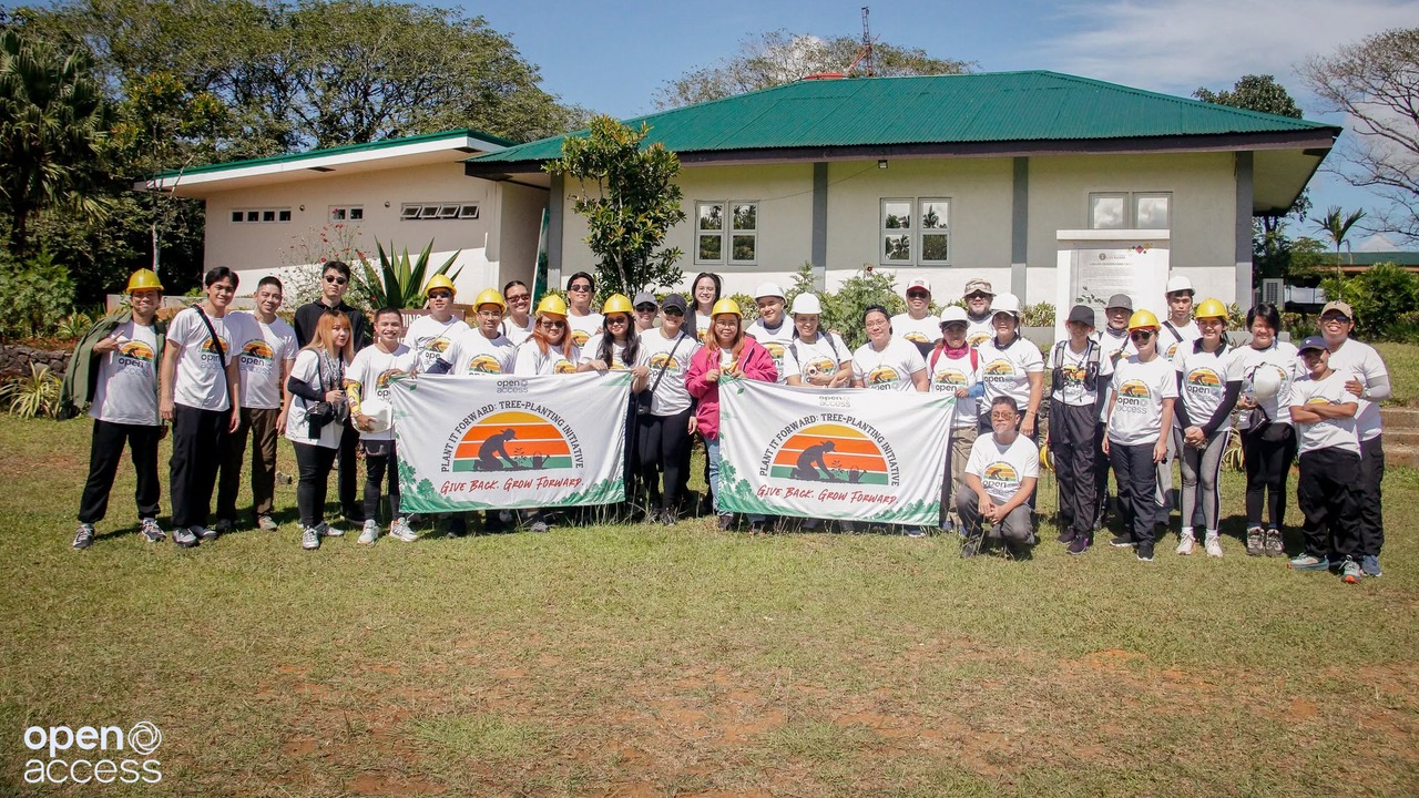 Open Access employee volunteers with Plant It Forward banners at the UP Laguna-Quezon Land Grant
